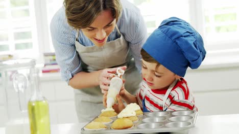 Mutter-Hilft-Jungen,-Cupcake-Mit-Sahne-Zu-Dekorieren