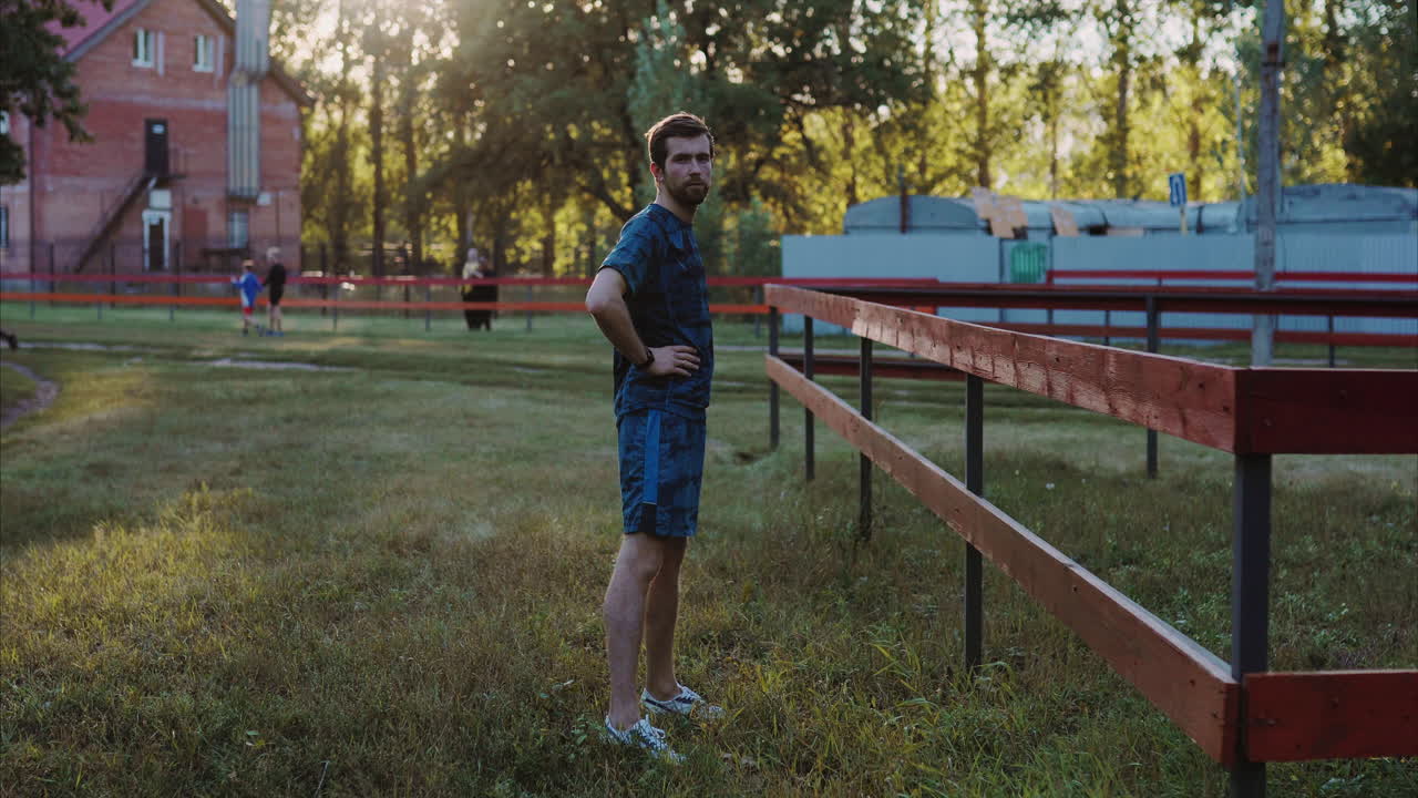hombre de pie junto a una valla en un parque