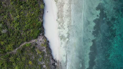 Playa-De-Kusini-En-La-Isla-De-Zanzíbar-Oriental-Tanzania-áfrica-Con-Arrecife-De-Coral-Y-Costa-Rocosa,-Toma-De-Rotación-Aérea-Mirando-Hacia-Abajo