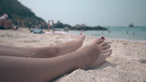 woman-with-accurate-pedicure-relaxes-lying-on-warm-sand