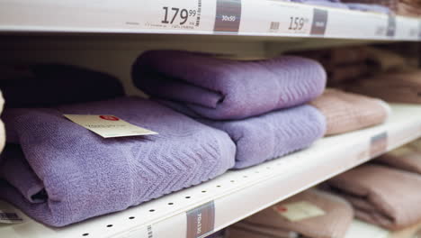 view of neatly arranged purple towels on store shelves. captured with a handheld camera, this video showcases the organized display and variety of towels in a retail environment