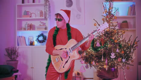 man playing guitar by decorated christmas tree at home