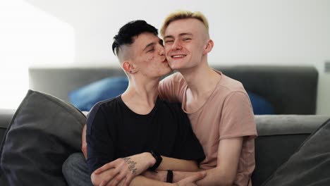 Young-happy-smiling-homosexual-male-gay-couple-is-enjoying-time-together-is-hugging-on-the-sofa