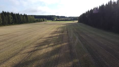 Drone-flying-fast-and-low-over-farmland-and-forest-in-Finland-national-park