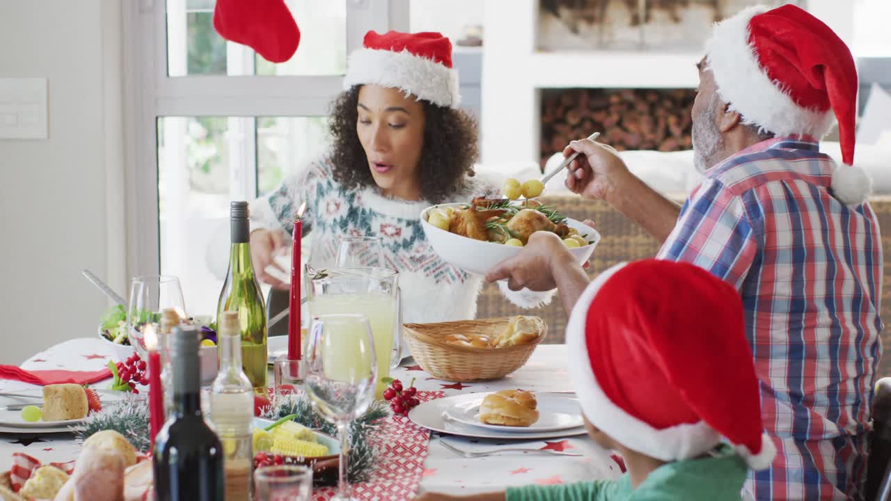 feliz familia afroamericana de varias generaciones con sombreros de papá noel y celebrando en la cocina