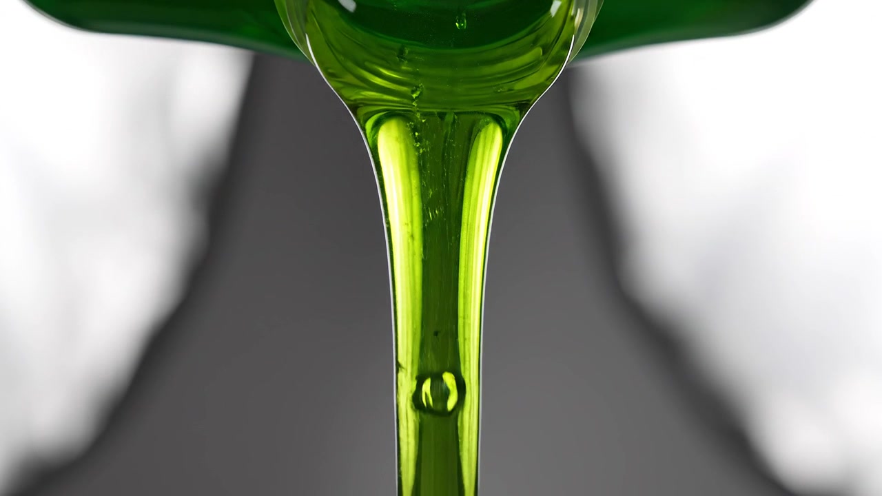 Primo piano di liquido verde denso che si versa da una bottiglia di plastica