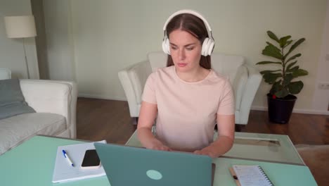 woman teenager in headphone using laptop for online study from home office