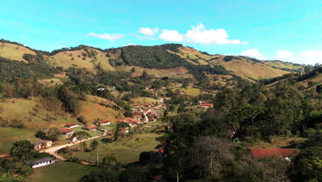 Drohnenansicht-Der-Landschaft-über-Einem-Wohnviertel-In-Einem-Bergigen-Tal-Auf-Dem-Land-Mit-Der-Hauptstraße-In-Rosário-Minas-Gerais,-Brasilien