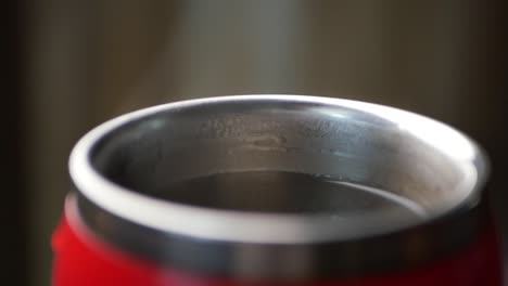 close-up of a red thermos mug with hot beverage inside