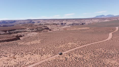 aerial, camper van on road trip driving on vast red desert in arizona