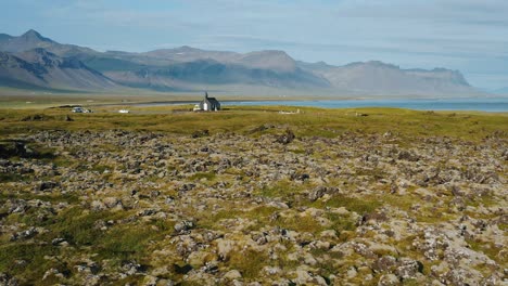 la iglesia de budakirkja en el parque nacional de snaefellsjoekull, islandia. imágenes aéreas de la órbita del círculo de drones.