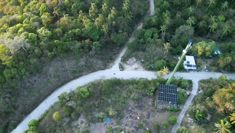 scooter bike riding along narrowed countryside road with solar panel green energy power plant in nature with palm tree aerial top down