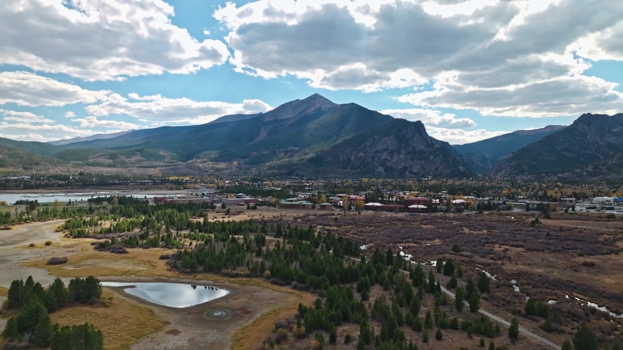 Visão geral de drone de um leito de lago seco com canais de água sinuosos e montanhas sob um céu nublado, Frisco, Colorado.