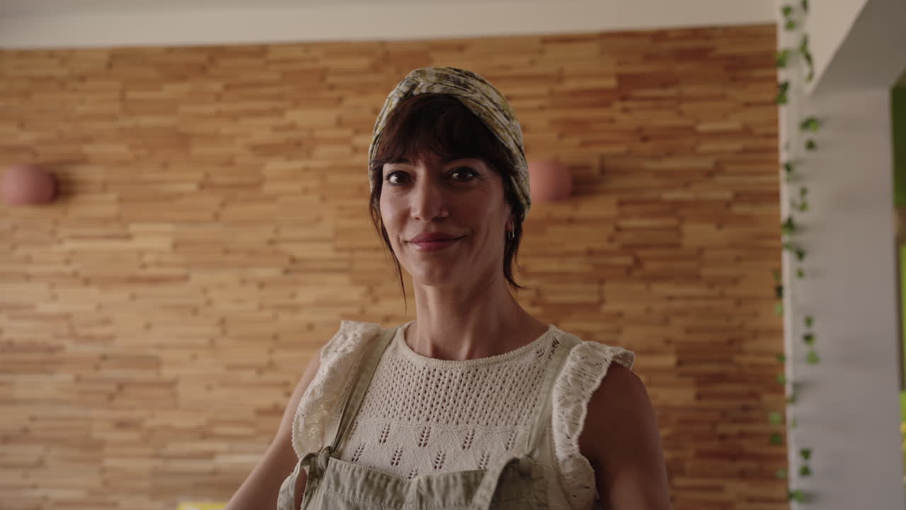 Donna felice che balla a casa e sorride alla telecamera. Autentico momento di vita che mostra gioia, autoespressione ed emozioni positive in un accogliente ambiente quotidiano.