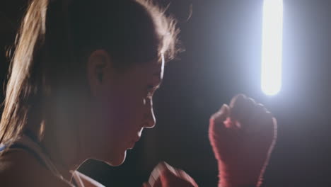 Boxer-woman-in-red-bandages-on-the-hands-of-and-blue-t-shirt-conducts-battle-with-of-practicing-the-speed-and-technique-strikes-hands.-Camera-movement-side-View.-Steadicam-shot