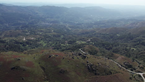 Single-road-at-passing-through-a-mountain-valley-leading-to-a-small-town-with-huts-and-farms