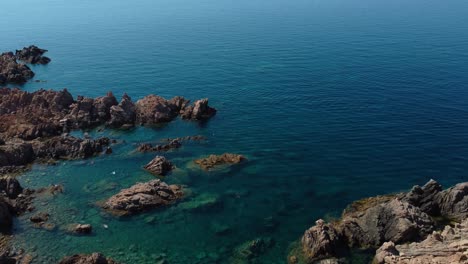 aerial of an idyllic natural coast beach rock bay on the tourist vacation island sardinia in italy with sun, clear blue turquoise and calm water close to capo testa