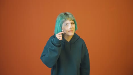 Young-woman-looking-at-camera-with-magnifying-glass.