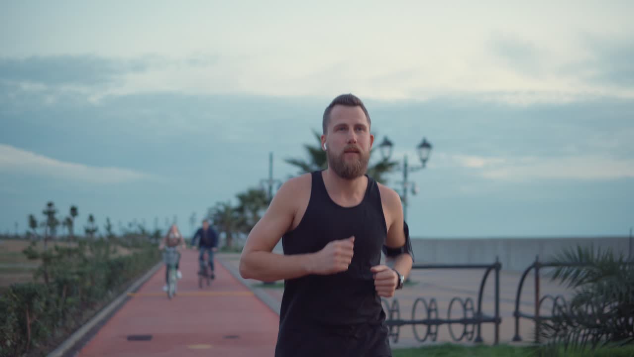 hombre corriendo por un camino de la ciudad al anochecer