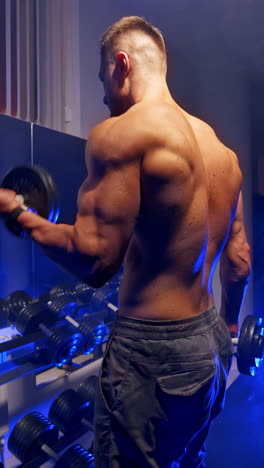 handsome man doing exercise. muscular man working out in gym doing exercises with dumbbells. vertical video