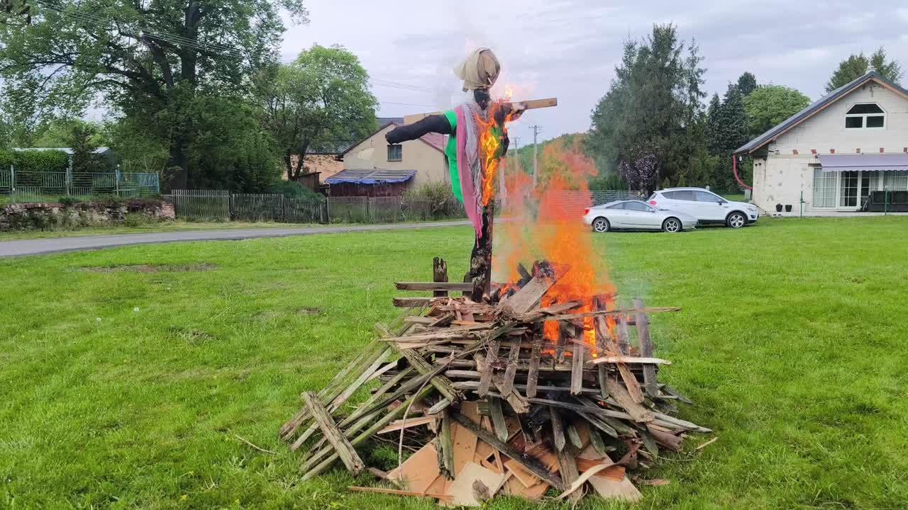 Brennende heksebilder på et tradisjonelt bål under feiringen av heksenes natt i et gresskledd uteområde med flammer, røyk og festlig vårstemning