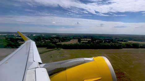 passenger point of view of yellow jet commercial airplane wing and engine during takeoff from london gatwick airport in uk