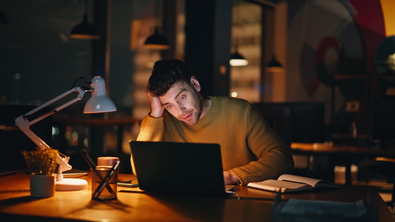 Tired man working late at night on a laptop