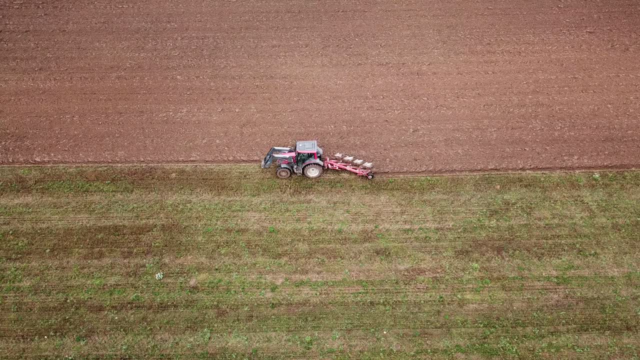 tiro de seguimiento aéreo cercano de un tractor arando el campo de un agricultor