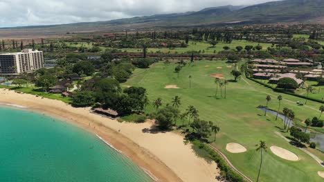 rotating aerial view of the kaanapali golf course over may's beach in maui, hawaii