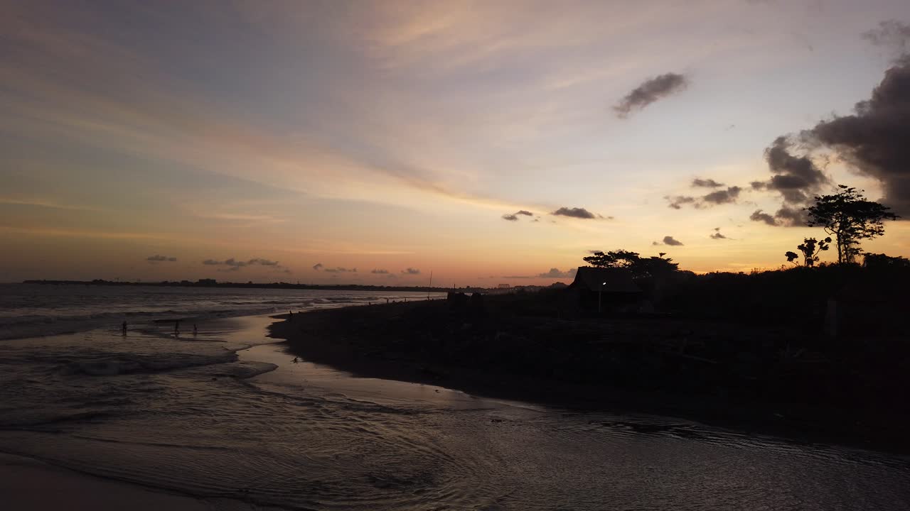 Silhouette dell'isola al tramonto, spiaggia di sabbia nera a Bali, Gianyar, Indonesia, cielo all'ora d'oro all'orizzonte di Ketewel. Viaggi e turismo.