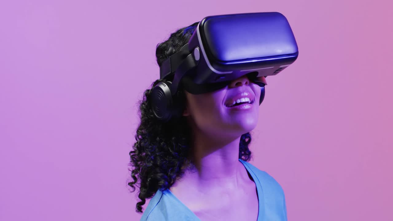 Video di una donna di etnia mista che utilizza un visore VR su sfondo rosa e viola