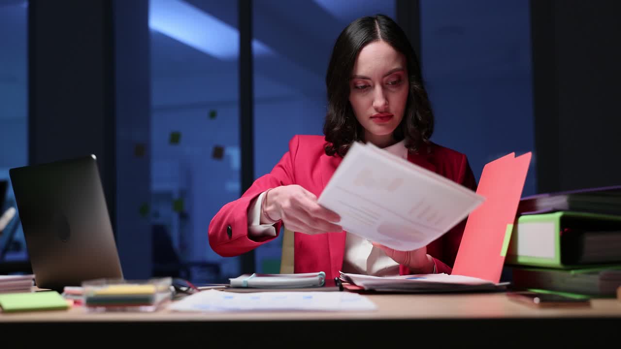 Businesswoman Working Late at Desk with Documents and Laptop
