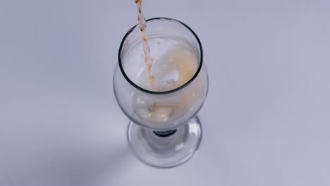 맥주가 흰색 배경에 있는 유리잔에 쏟아지고 있다