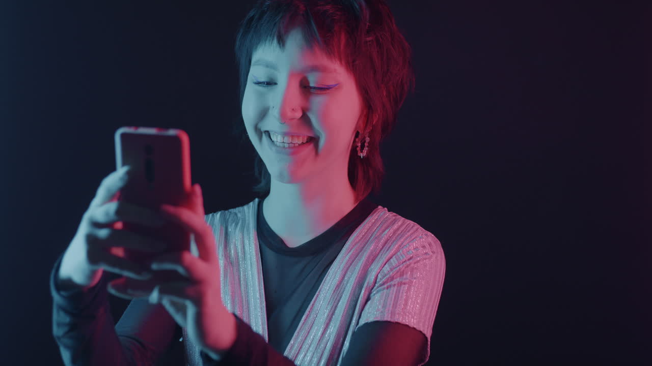 Neon-lit portrait of a young woman using a smartphone