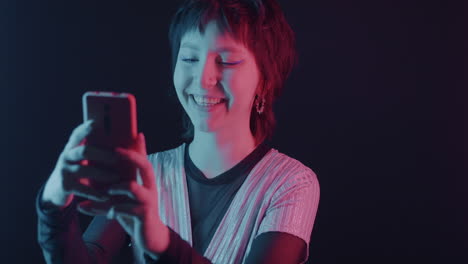 neon-lit portrait of a young woman using a smartphone