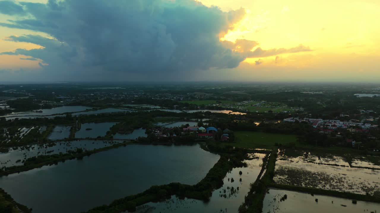 Aerial view of wetlands and farmland under a dramatic sunset sky in the Philippines. Perfect for nature, environmental, and cinematic projects