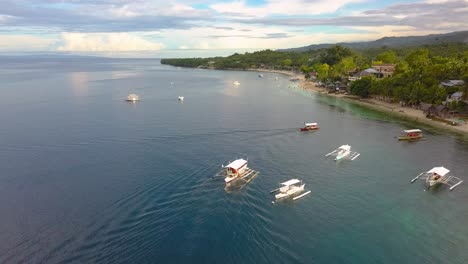 Aerial-dolly-forward-view-of-a-Bangka-boat-drifting-on-a-bay-from-a-village-in-Philippines,-drone-passin-by-shot