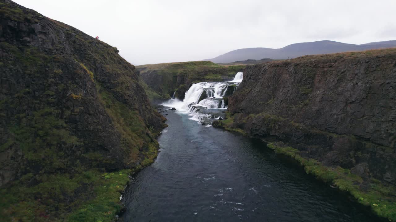 aéreo: vuelo a través del cañón del río que conduce a la cascada de reykjafoss que se presenta como una poderosa cascada de agua