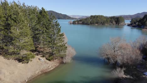 vista rápida del avión no tripulado sobre el lago artificial de la montaña panorámica día soleado de invierno