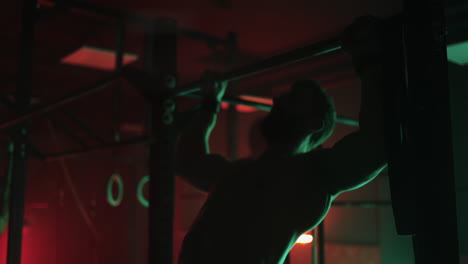 Zwei-Männer-Und-Eine-Frau-Machen-Im-Fitnessstudio-Gemeinsam-Klimmzüge-An-Der-Reckstange-Im-Dunklen-Neonlicht.-Atmosphäre-Von-Fitness-Und-Training