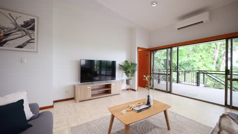 luxurious living lounge room with large sliding glass doors leading out onto treetop balcony in architecturally designed home