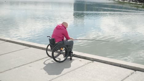 persona con discapacidad física que utiliza silla de ruedas para pescar en el muelle de pesca