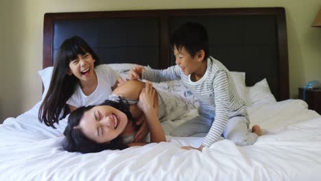 mother and kids having fun on bed in bedroom 4k