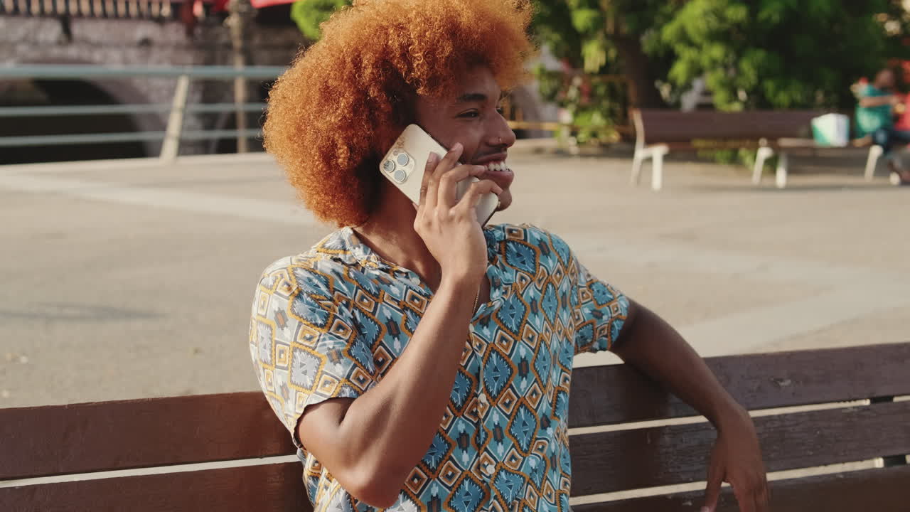 Mann, der auf einer Bank mit dem Handy telefoniert