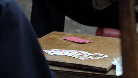 Three-men-finish-playing-a-card-game-hand-on-the-street-on-an-improvised-table-in-Chongqing-China,-locked-shot