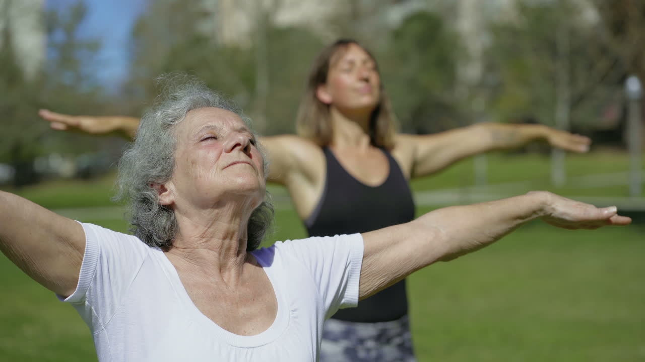 dos mujeres tranquilas de pie en el prado y practicando yoga.
