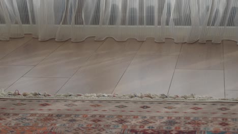 closeup of a rug on a wooden floor with a white curtain in the background