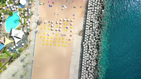 playa calheta con sombrillas amarillas y blancas alineadas en la arena frente al agua azul clara