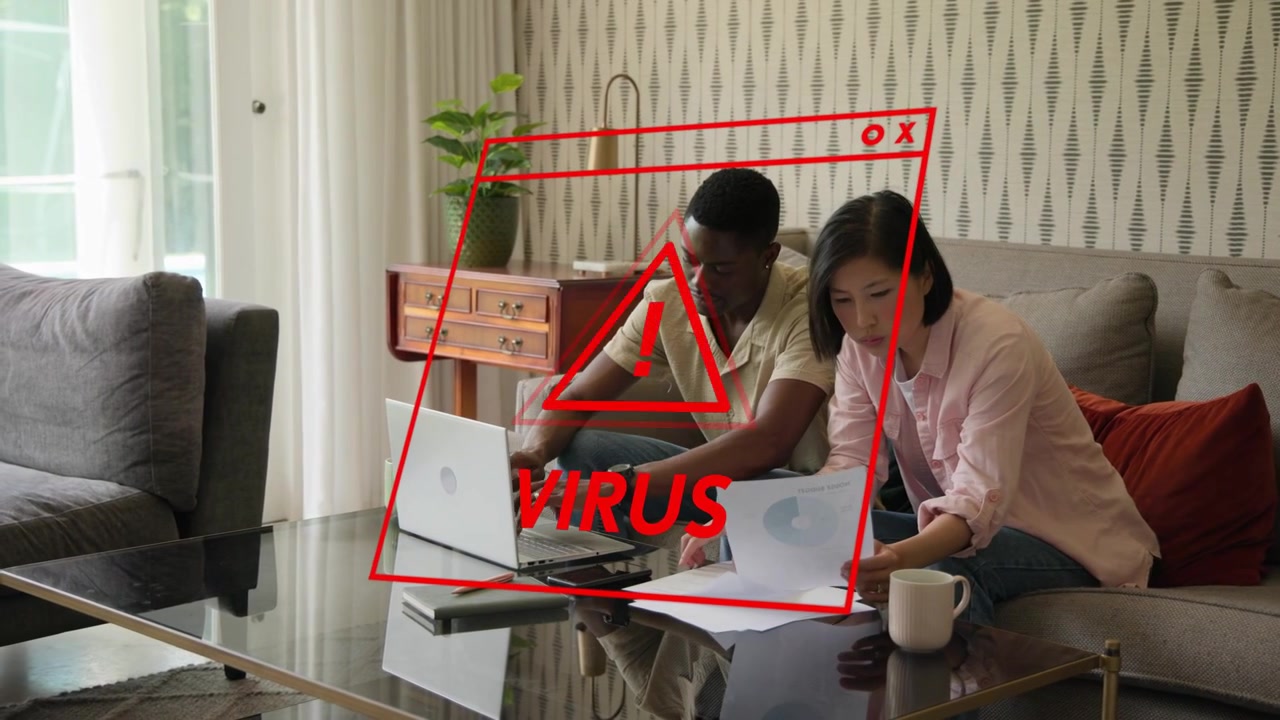 Couple sitting on couch sorting finance bills, red virus warning flashing laptop causing man typing
