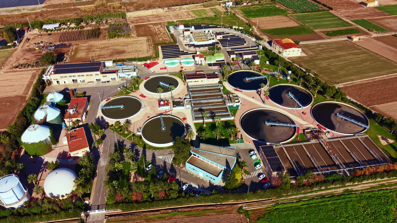 Water treatment facility located in an agricultural area with various tanks and structures for processing water during a sunny day